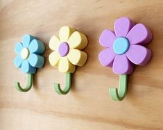 three flower shaped hooks are hanging on the wall