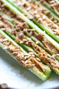 asparagus with peanut butter and walnuts on a white plate, ready to be eaten