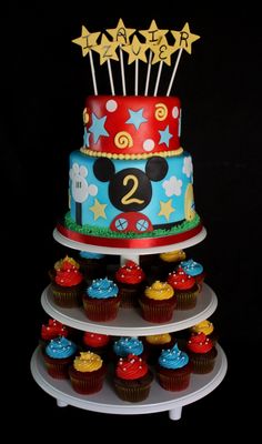 a mickey mouse cake with cupcakes and stars on the top for each tier