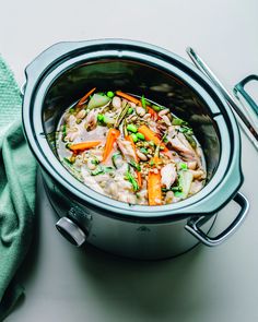 a pot filled with chicken and vegetables on top of a table next to a fork