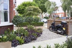 a motor scooter parked next to a wooden planter in front of a house