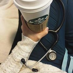 a person holding a cup of coffee with a stethoscope attached to it