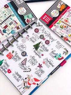 three notebooks with christmas stickers on them next to a pencil and paper clip