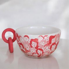 a red and white bowl sitting on top of a table next to a pair of scissors