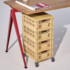 a wooden table with four drawers on it and a red metal frame next to it