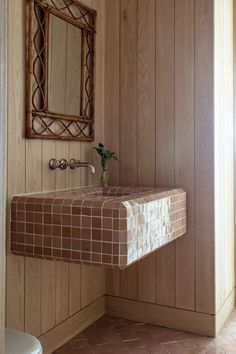 a bathroom with wooden paneling and a mirror on the wall next to a toilet