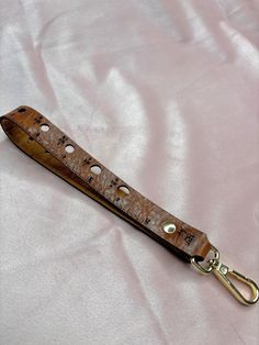 a wooden ruler with holes in it laying on a pink cloth covered bedding area