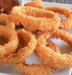 fried onion rings on a plate with ketchup