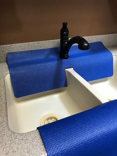 a bathroom sink with blue towels on the edge and a black faucet next to it