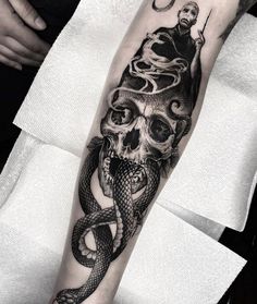 a man with a snake and skull tattoo on his arm