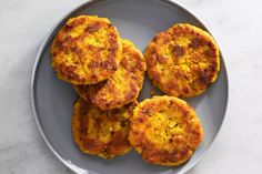 four crab cakes on a gray plate with a white marble table top and silver trim