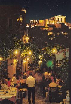 people are sitting at tables in an outdoor restaurant