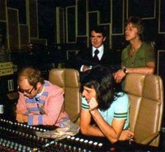 three people sitting in front of a mixing desk