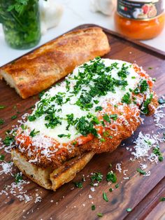 two pieces of bread with sauce and parmesan cheese on them sitting on a cutting board