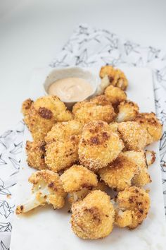 some fried food on a white plate with dipping sauce