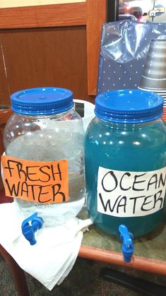 two plastic jars with labels on them sitting on a table