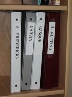 three binders are sitting on top of a book shelf