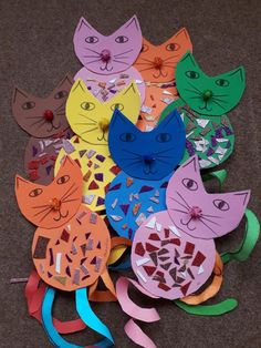 many different colored paper cats are on the ground with one cat's head cut out