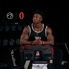 a man sitting on top of a white stool holding a black and red duffel bag