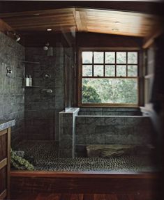 a bathroom with a large window and tiled walls, along with a walk in shower