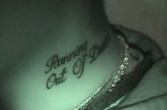 a woman's neck with the words running out of time tattooed on her chest