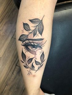 a woman's leg with an eye and leaves tattoo on the side of her leg