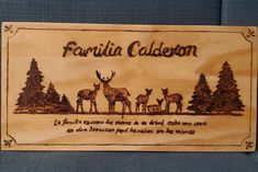 a wooden plaque with an image of some deer in the woods on it's side