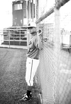 a young baseball player is leaning against the fence