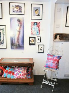 a living room with pictures on the wall and a chair in front of a coffee table