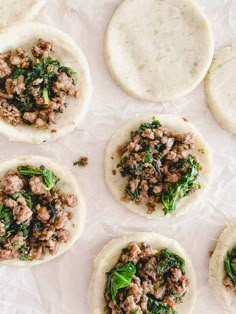 several pita breads with meat and spinach on top