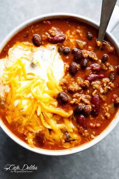 chili and cheese soup with sour cream in a white bowl on a gray table top