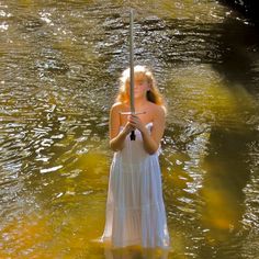 a woman standing in the water holding an umbrella