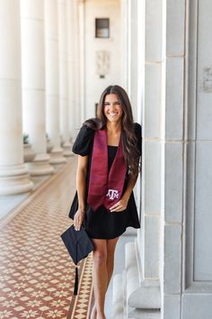 a woman standing next to a pillar wearing a black dress and red scarf with the letters tc on it