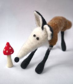 a needle - felt fox and mushroom on a white background