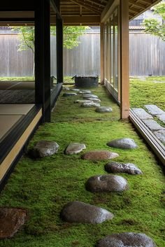 the inside of a house with moss growing on the floor and rocks in the grass