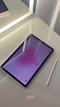 a tablet with a pen sitting on top of it next to a phone and mirror