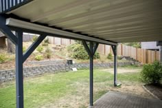 a covered patio with grass and trees in the background