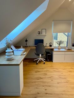 an attic office with wooden floors and skylights above the desk area is well lit