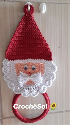 a red and white knitted santa claus head on a doorknob with a ring