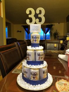 a three tiered cake with beer cans stacked on top and the number 33 in gold