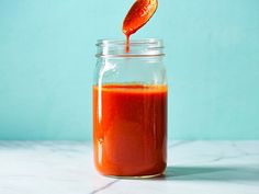 a jar filled with red liquid on top of a white counter next to a blue wall