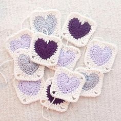 small crocheted coasters with purple and white hearts on them sitting on a table