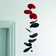 a white wall with some red and black shapes hanging from it's side next to a door