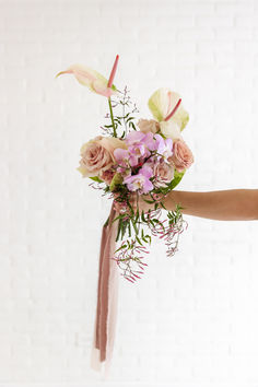 A Bouquet Outstretched Filled With Anthurium, Roses, Orchids, Jasmine, Greenery.