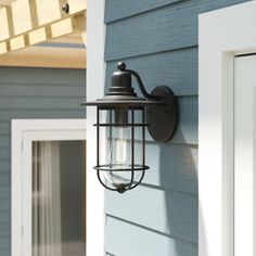 an outdoor light on the side of a house next to a white door and window