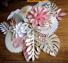 some paper flowers and leaves on a wooden floor