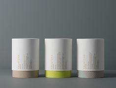 three white and green coffee cups sitting on top of a gray table next to each other