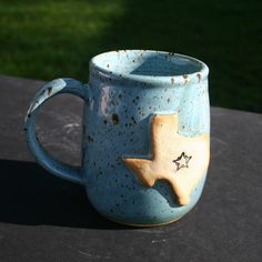 a blue mug with a star on it sitting on top of a black table outside