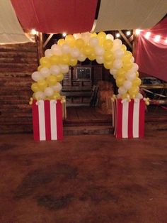 two red and white striped boxes with balloons in them sitting on a brown tablecloth covered floor