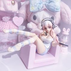 a doll sitting on top of a pink chair next to a stuffed animal and other toys